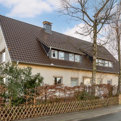 Einfamilienhaus mit Flachdachziegel J11v in dunkelbraun in der Gesamtansicht mit Gartenzaun.