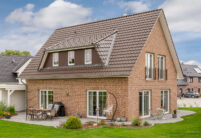 Vooraanzicht van een kapiteinswoning met FD-dakpan J11v in donkerbruin met zicht op het terras.