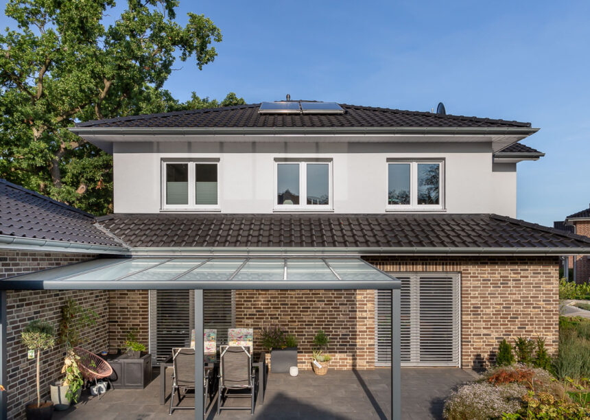 Kleine Stadtvilla mit Flachdachziegel J11v in altschwarz mit überdachter Terrasse.