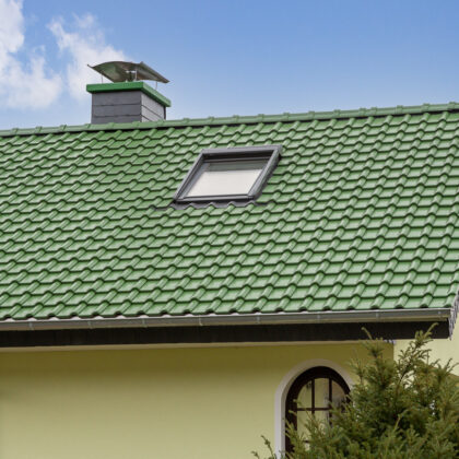 Sanierter Bau aus den 70/80er Jahren mit auffallend grünem Dach mit Fokus auf die Firstreihe und Dachfläche.
