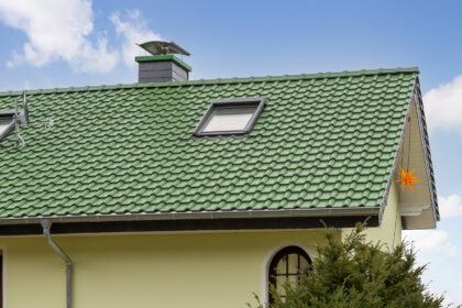 Sanierter Bau aus den 70/80er Jahren mit auffallend grünem Dach mit Fokus auf die Firstreihe und Dachfläche.