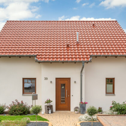 Einfamilienhaus mit Satteldach in toskanarot matt und Holztüre